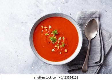 Tomato soup with fresh herbs and pine nuts in a bowl. Grey stone background. Top view. - Powered by Shutterstock