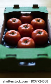 Tomatoes in a cardboard box on a wooden table