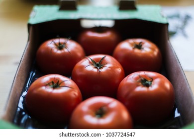 Tomatoes in a cardboard box on a wooden table