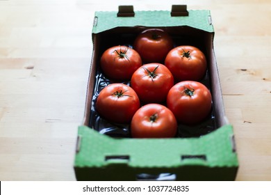 Tomatoes in cardboard box on a wooden table