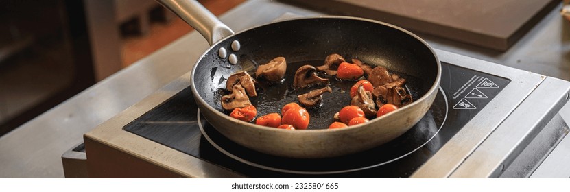 Tomatoes and mushrooms is cooking in frying pan in restaurant kitchen - Powered by Shutterstock