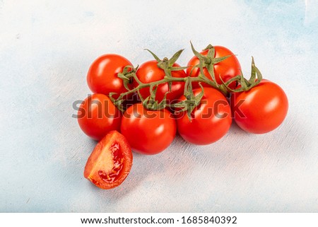 Tomatoes on a branch (vine tomatoes). Tomatoes on the vine and on a blue wood background. Beautiful tomatoes with a beautiful green branch.