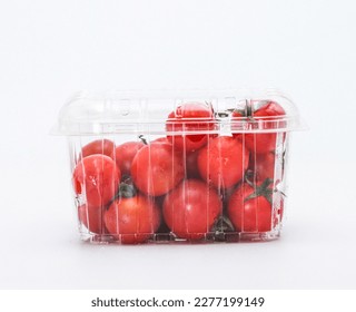 Tomatoes in a plastic container. Plastic container with ripe cherry tomatoes on white background.