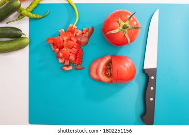 Tomaten, geschnitten mit Messer auf hellblauem Tisch mit Gurken, Pfeffer und Karotten