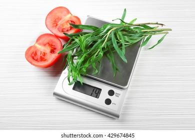 Tomatoes and tarragon with digital kitchen scales on wooden background