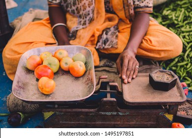 Tomatoes weighed using old weighing balance in a farmer's market. Vendor woman using cast iron weights. - Powered by Shutterstock