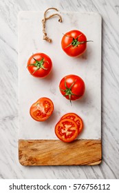 Tomatoes (whole and sliced) on marble cutting board. Top view