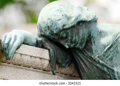 Tomb with a bronze statue of a grieving woman that is covered with green patina from years of exposure to the elements.