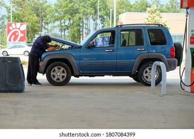 Tomball, TX / USA - September 01, 2020: Man Working On His Car That Is Broken Down In A Gas Station Parking Lot. Hood Up, Wont Start, Car Trouble.