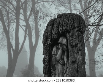 Tombstone with a crying girl. Melancholic mood in a foggy old Christian cemetery.