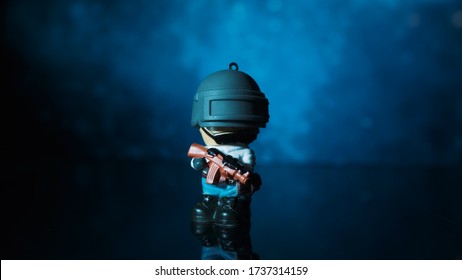 TOMSK, RUSSIA - May 21, 2020: Toy little man from the PUBG game with a rifle stands on a table against the color background