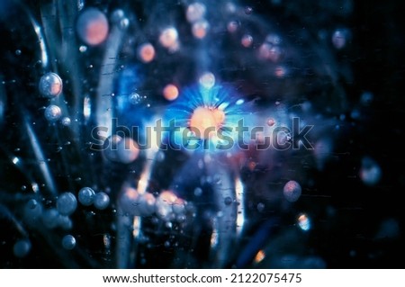 Toned composition of ice bubbles in the thickness of the ice. Colored background. The concept of subatomic particles or cosmic bodies. Abstract image. Selective focus.