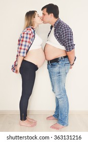 Toned Funny Portrait Of Pregnant Couple Standing Face To Face And Kissing