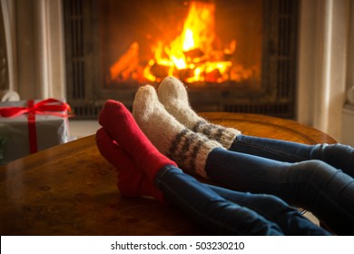 Toned image of couple wearing woolen socks relaxing by the fireplace at house - Shutterstock ID 503230210