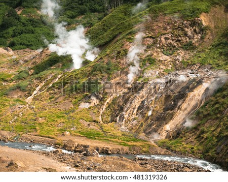 Toned image Geyser Valley with the river flowing at the bottom against the backdrop of huge volcano on Kamchatka in Russia