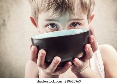 Toned Image Of A Hungry Child Holding An Empty Bowl.