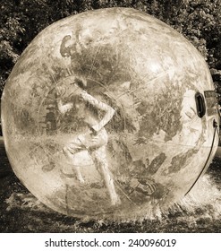 Toned Image Of A Little Boy Running Inside The Water Bowl On A Background Of Foliage