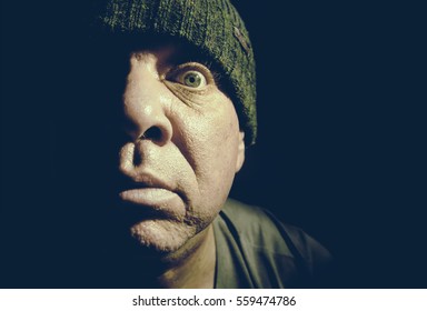 Toned Low Key Portrait Of A Surprised Man With Wide Eyes. His Face Lit Up Halfway.