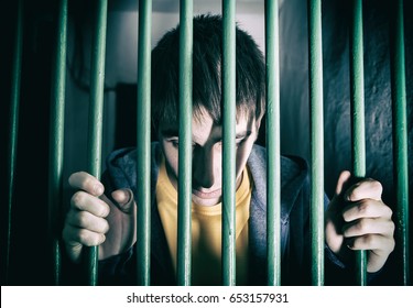 Toned Photo of Jailed Young Man behind bars in a Cell