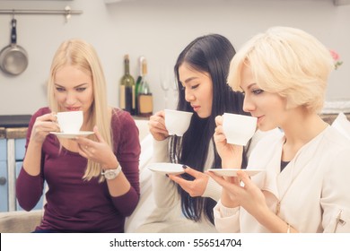 Toned Picture Of Pretty Ladies Drinking Tea Or Coffee From White Cups. Beautiful Women Spending Free Time In Company Of Girls.