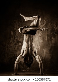 Toned picture of young man with naked torso doing acrobatic movements