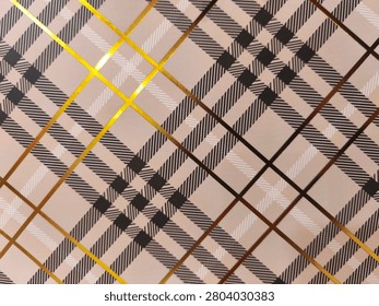 Toned plaid pattern with bold intersecting lines. Golden and brown stripes contrast against soft beige background. Geometric design repeats across entire surface. Suitable for fashion, interior