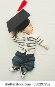 Toned portrait of cute baby boy posing in black graduation cap