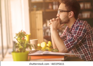 Toned Profile Image Of Handsome Freelance Man Looking At Window And Thinking About New Business Projects Or Strategies In Restaurant Or Cafe.