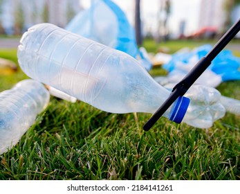 Tongs for cleaning garbage. Lawn cleaning from plastic bottles. Close-up