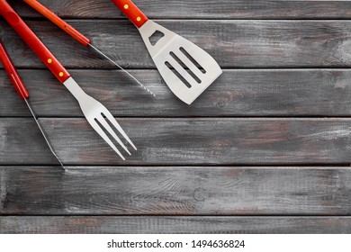 Tongs, fork, spatula for barbecue and grill on wooden background top view copyspace
