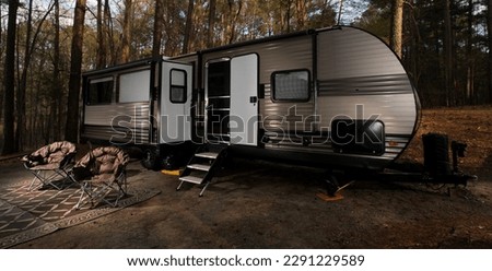 Tongue pulled camping trailer set up for the night in North Carolina with a pair of chairs 
