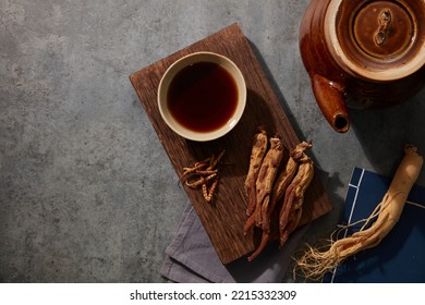 Tonic tea made with fresh ginseng and dried red ginseng is placed on a wooden podium beneath the cement floor. - Shutterstock ID 2215332309