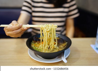 Tonkotsu Ramen - A Bowl Of Japanese Noodles Soup Made From Stock Based On Pork Bone Broth, Topped With Sliced Braised Pork (Chashu), Shredded Carrots And Spring Onions On Wooden Table.