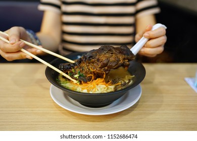 Tonkotsu Ramen - A Bowl Of Japanese Noodles Soup Made From Stock Based On Pork Bone Broth, Topped With Sliced Braised Pork (Chashu), Shredded Carrots And Spring Onions On Wooden Table.