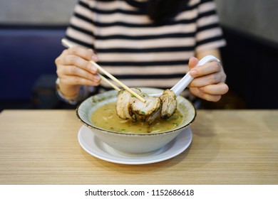 Tonkotsu Ramen - A Bowl Of Japanese Noodles Soup Made From Stock Based On Pork Bone Broth, Topped With Sliced Braised Pork (Chashu), Shredded Carrots And Spring Onions On Wooden Table.