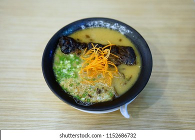 Tonkotsu Ramen - A Bowl Of Japanese Noodles Soup Made From Stock Based On Pork Bone Broth, Topped With Sliced Braised Pork (Chashu), Shredded Carrots And Spring Onions On Wooden Table.