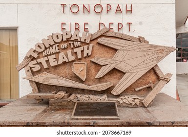 Tonopah, Nevada, US - May 17, 2011: Closeup Of Beige Wooden Sculpture In Front Of White New Tonopah Fire Department Building Sjpowomg Stealthj Airplane Model.