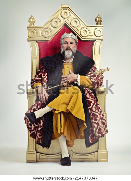 I took the throne peacefully. Studio\
shot of a richly garbed king sitting on a\
throne.