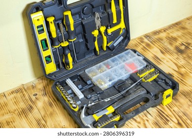 Tool kit featuring various hand tools such as screwdrivers and pliers, with a compartment for screws, placed on a wooden workbench surface