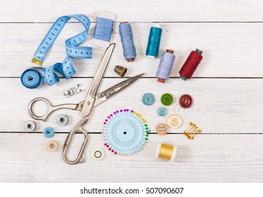 Tools and accessories for sewing on light wooden background. Top view.