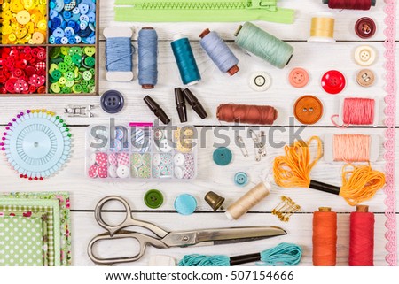 Tools and accessories for sewing on light wooden background. Top view. Flat lay composition.