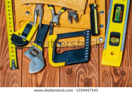 Tools in the bag for master builder prepared before work on vintage brown wooden boards