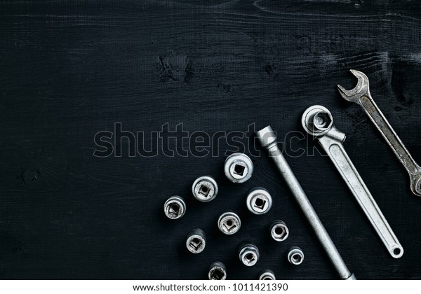 Tools for car repair in\
Workshop. Car repair equipment on black wooden background in car\
repair shop