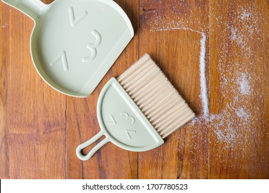 Tools For Cleaning The House. A Sweeping Brush With Artificial Bristles And A Purple Dustpan Against The Background Of The Vinyl Floor Covering In The Kitchen Close Up During Cleaning.