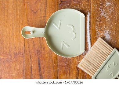 Tools For Cleaning The House. A Sweeping Brush With Artificial Bristles And A Purple Dustpan Against The Background Of The Vinyl Floor Covering In The Kitchen Close Up During Cleaning.