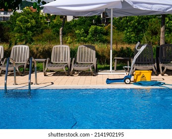 Tools For Cleaning The Pool. Hose And Bucket With The Inscription Caution Wet Floor.  Concept Photo  Pool Cleaning, Hotel Staff, Service.