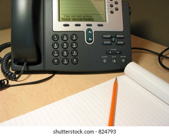 Tools of customer support on the office desk- IP phone, pencil, notepad