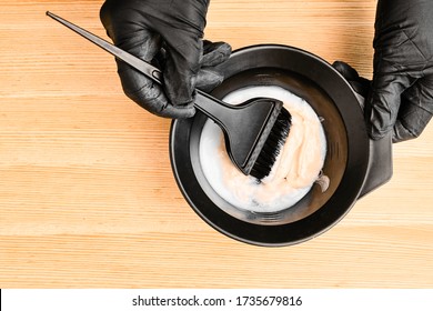 Tools for hair dyeing in hairdresser hands on the wooden background. Colouring of hair at home - Powered by Shutterstock