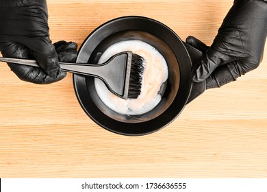 Tools for hair dyeing in hairdresser hands on the wooden background. Colouring of hair at home - Powered by Shutterstock