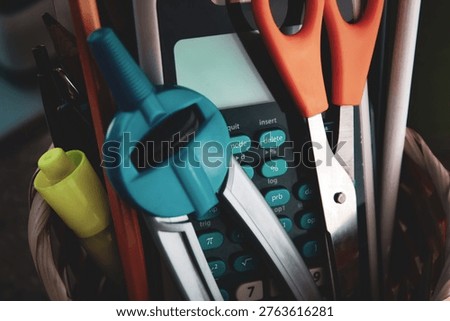 Tools of learning background. A calculator, compass, scissors, and school supplies in a basket with soft focus. Science Technology Engineering and Math themes.